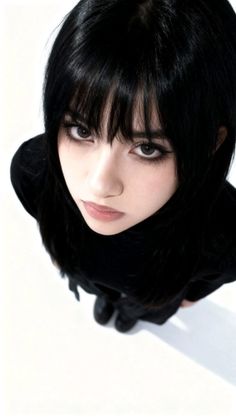 Woman with black hair and dark makeup looking up from a high angle