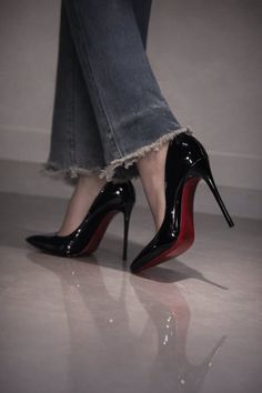 Person wearing black high heels with red soles and cropped denim jeans