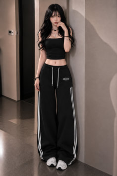 Woman with long black hair wearing a black crop top and sweatpants indoors