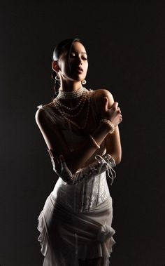Woman in a white corset and pearl jewelry with dramatic lighting