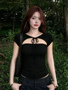 Woman with long hair wearing a black cutout top outdoors