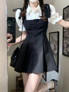 Person in a black dress and white shirt taking a mirror selfie