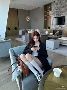 Woman with long hair sitting in a modern indoor setting, looking at her phone