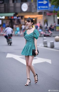 Woman in a green floral dress and high heels walking on a street