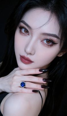 Woman with long black hair and dark makeup wearing a blue ring