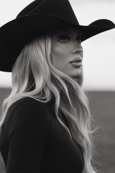 Woman with long blonde hair wearing a cowboy hat in a black and white outdoor portrait