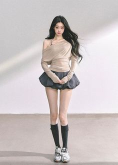 Woman with long black hair wearing an off-shoulder top and mini skirt indoors