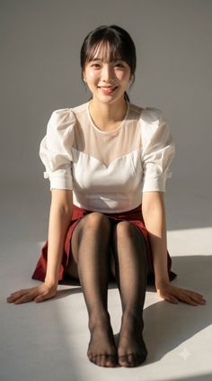 Woman in a white blouse and red skirt sitting on the floor with soft lighting