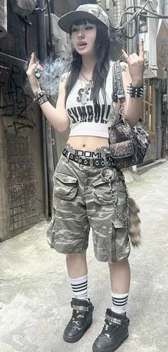 Person in a camo hat and cargo shorts with a crop top in an alleyway
