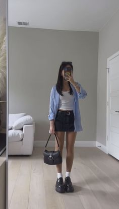 Woman in a striped shirt and mini skirt taking a mirror selfie indoors