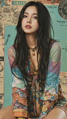 Woman with long dark hair wearing a patterned dress and gold jewelry