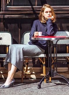 Woman with short hair sitting at an outdoor cafe table with a coffee cup