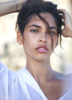Woman with sandy skin and wet dark hair in a white shirt