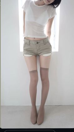 Woman in a sheer white top, short shorts, and thigh-high stockings indoors