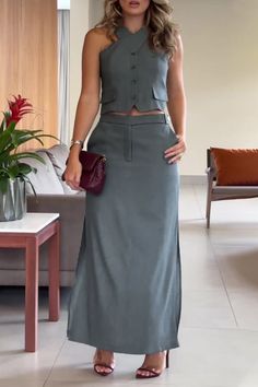 Woman in a matching green sleeveless top and long skirt holding a clutch bag