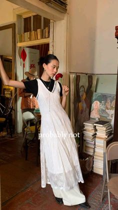 Woman in a white lace dress holding a red rose indoors