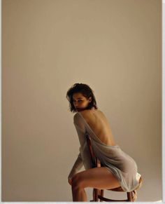 Woman in a sheer top with an exposed back, sitting on a chair