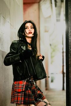 Woman in a leather jacket and plaid skirt with fishnet stockings in an urban setting