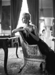 Woman in an elegant dress sitting in a chair with backlight from a window