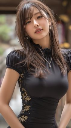Woman with long brown hair wearing a black dress with gold embroidery