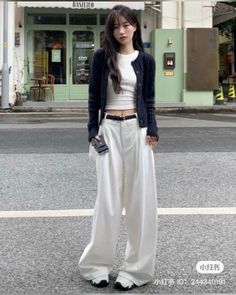 Woman in a black cardigan and white wide leg pants on a street