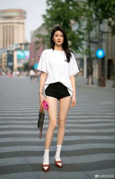 Woman in a white t-shirt and black shorts standing on a street