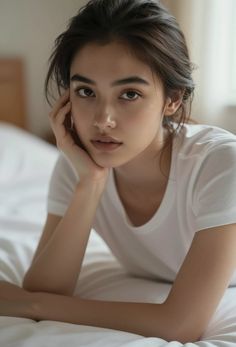 Woman in a white t-shirt lying on a bed with soft lighting