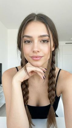 Woman with long braided hair and dark nails posing indoors