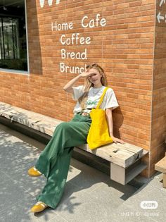 Woman with long hair sitting on a bench in front of a brick wall cafe