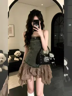 Woman in a dark green top and ruffled skirt taking a mirror selfie