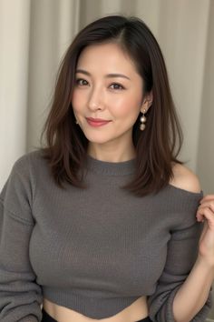 Woman with medium hair wearing an off-shoulder top and pearl earrings