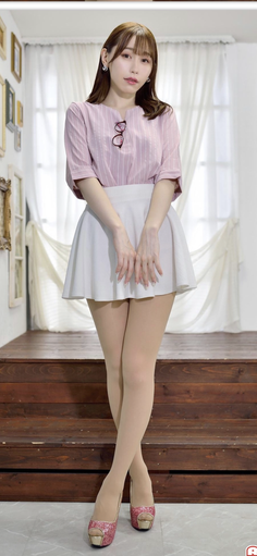 Woman in a pink striped shirt and white skirt standing indoors