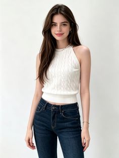 Woman with long brown hair wearing a white cable knit halter top and dark jeans