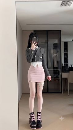 Person in a school uniform with a pink skirt and platform boots taking a mirror selfie