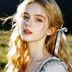 Blonde woman with blue eyes and a ribbon in her hair, outdoors with soft lighting