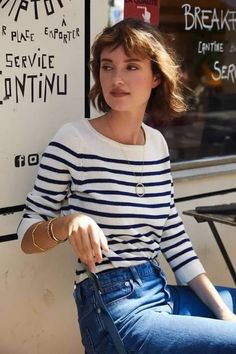Woman with short hair wearing a striped shirt and blue jeans outdoors