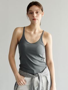 Woman in a gray tank top and white pants with a sweater tied around her waist