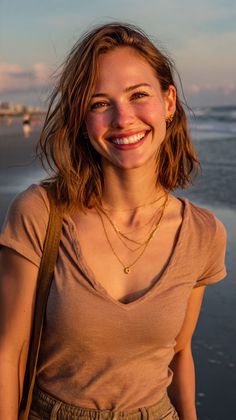 Smiling woman with short hair and freckles on a beach at golden hour
