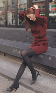 Woman in a red dress and black tights sitting outdoors