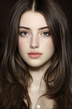 Close-up portrait of a young woman with long brown hair and green eyes