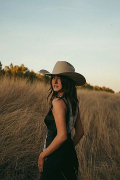 Woman in a cowboy hat in a field of tall grass at golden hour