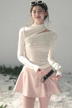 Woman in a white top and pink skirt with sunglasses on her head outdoors