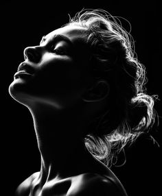 Black and white portrait of a woman with dramatic backlight and bare shoulders