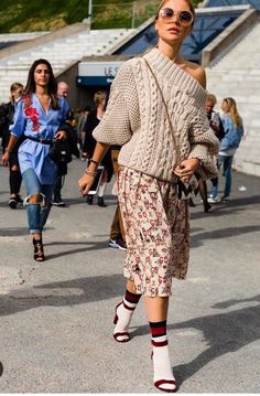 Woman in an off-shoulder sweater and patterned skirt walking outdoors