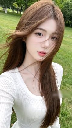 Woman with long brown hair wearing a white top outdoors