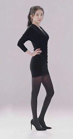 Woman in a black dress and tights posing in a studio