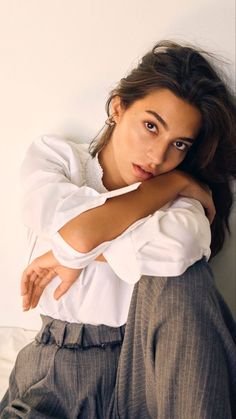 Woman with long hair wearing a white shirt and striped pants, looking at the camera