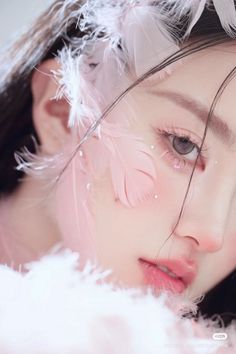 Close up of a person with pink feathers and sparkling details on their face