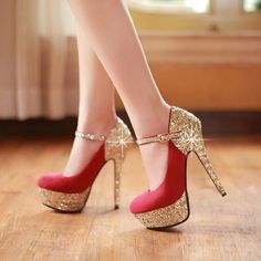 Pair of red and gold glitter high heels with ankle straps on a wooden floor
