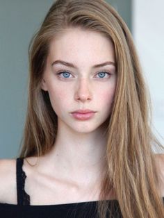 Woman with long blonde hair and blue eyes wearing a black top